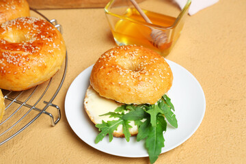 Wall Mural - Plate of tasty bagels with butter and arugula on beige background