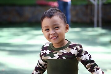 Asian boy about two years old wear a Military pattern shirt was standing smiling happily.