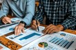 © momostudio - Two People Analyzing Financial Data with Charts and Graphs