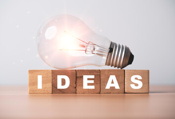 Fototapete - Glowing lightbulb on ideas wording for creative thinking and problem solving solution concept.