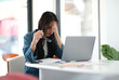 © ijeab - A woman is sitting at a desk with a laptop and a stack of papers