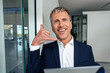 © Westend61 - Smiling businessman making call me gesture at office