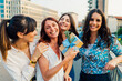 © Westend61 - Cheerful woman holding gift box with friends in front of buildings