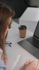 Poster - The diligent student at the university desk is fully focused on taking detailed notes using a laptop, showcasing their commitment to academics through a dedicated approach to learning