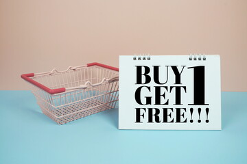 Wall Mural - Buy 1 Get 1 Free!!! Sale promotion with trolley shopping cart on pink and blue background