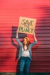 © VISTA by Westend61 - Young teenage girl protesting in front of red corrugated iron