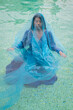 © Milou Dirks - asian woman in a blue dress emerged in blue water pf swimming pool in art portrait