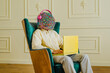 © VISTA by Westend61 - Man with mask of chaotic thoughts using laptop and listening music sitting on chair