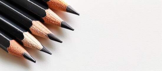 Poster - Black pencils on a white backdrop with space for text in the image. copy space available