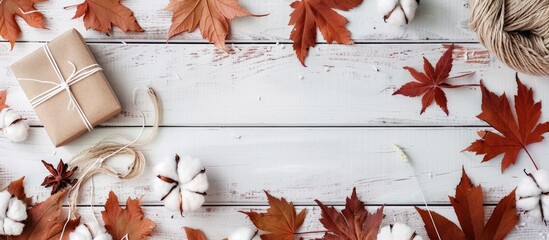 Aufkleber - An arrangement featuring fallen maple leaves a gift box white flowers and cotton on a white wooden surface ideal for a copy space image