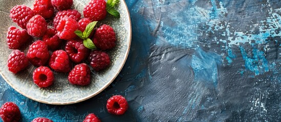 Poster - A ceramic plate with fresh raspberries on a rustic blue desk providing a perfect background for a copy space image
