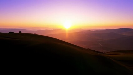 Sticker - The sun making its final descent behind the rolling hills casting long shadows and creating a peaceful ambiance.