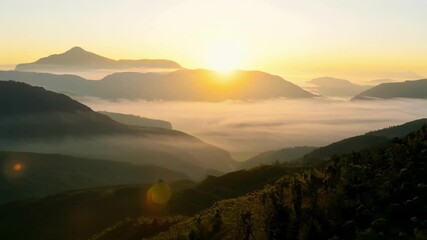 Poster - The sun rising over misty mountain valleys casting a golden light over the serene landscape.