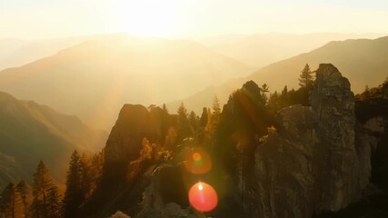 Poster - The suns rays slowly creep down the slopes illuminating the trees and rocks along the way.