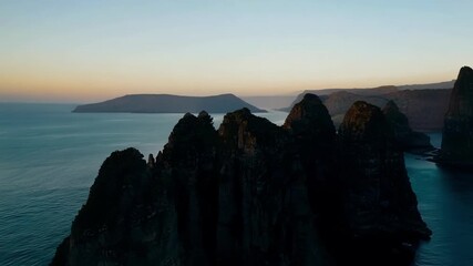 Poster - Soaring over the rocky spires and cliffs the last traces of sunlight reflecting off the water as night begins to descend.