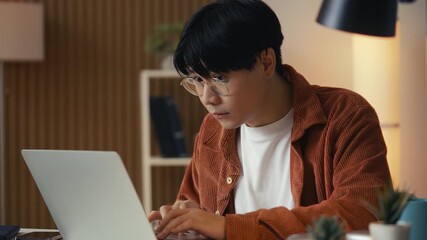 Asian male freelancer working on laptop, having problem with computer program