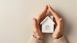 © Seksan - Hands encircling a model house, depicting the security and protection of home insurance
