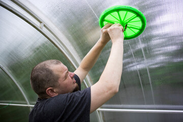 Wall Mural - A man is fixing a green frisbee on a ceiling