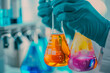 © AnggalihPs - A scientist holding beakers with colorful liquids in them.