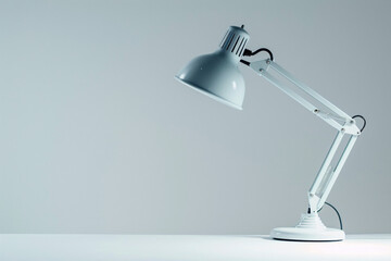 White desk lamp with adjustable arm and a lightbulb on a white table.