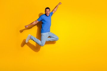 Full size photo of pretty young male flying superman have fun wear trendy blue outfit isolated on yellow color background