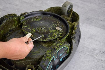 A man changes the blades of a robotic lawn mower.