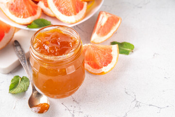 Sticker - Homemade grapefruit jam, sweet pink grapefruit marmalade in small jar, with grapefruit slices and mint leaves on white table background