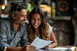 © Henrry L - A man and woman are sitting at a table looking at a piece of paper