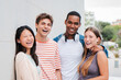 © Jose Calsina - two handsome men and two teenage women looking at camera standing at university campus. Group of international friends laughing together. Portrait of young multiracial people smiling on a meeting