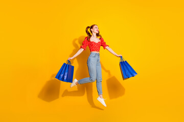 Canvas Print - Full size photo of pretty young girl hold shopping bags jump look empty space wear red retro outfit isolated on yellow color background