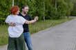 © MarijaBazarova - Happy dancers curling in dance in park. Romantic couple, woman with red hair and man in dark t-shirt and blue jeans dancing on street, on forest background. International dance day.