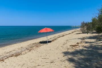 beautiful beach in Ionian Calabria, with lonely red sun umbrella