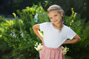 Happy  adorable child girl in a dress with pockets in which daisy bouquet  in her pocket in summer outdoor. copy space. Earth Day. World Environment Day. world white chamomile day. aroma therapy. 