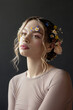 © angel_nt - A young woman with blonde hair, wearing a plain long-sleeve shirt, gazes upwards as she poses in front of a dark background. She has flowers in her hair and on her face