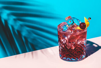 Wall Mural - Red cocktail drink with liqueur and aperitif, ice, rose sparkling wine with zest, blue background