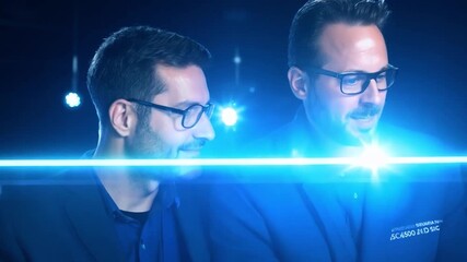 Poster - Two men are interacting with a digital interface, with blue glowing lines representing data.