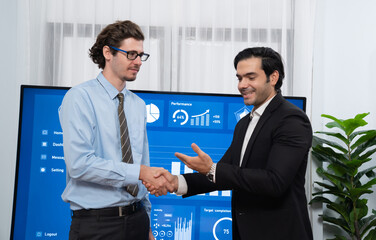 Two businessman shake hand in meeting room with coworker give cheerful applause. Team of analyst celebrate after successful significant progress on business strategic performance. Habiliment