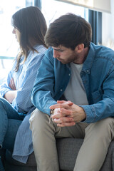 Close-up of unhappy young couple sitting apart have relationship problems, think about breakup or divorce. Family lovers, distraught men and women, avoid talking and suffer from betrayal in problems.