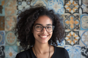 Wall Mural - Portrait of a happy young woman with curly hair and glasses, standing in front of a colorful patterned background