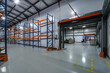© alhim - Spacious Industrial Warehouse With Shelving Racks and Open Loading Area.The interior of a large industrial warehouse features a wide-open space with shelving racks positioned against one wall.