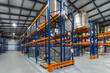 © alhim - Well-Organized Warehouse Displaying High Stacks of Palletized Goods Under Bright Lighting.The interior of a spacious warehouse is showcased with neatly arranged shelving units.