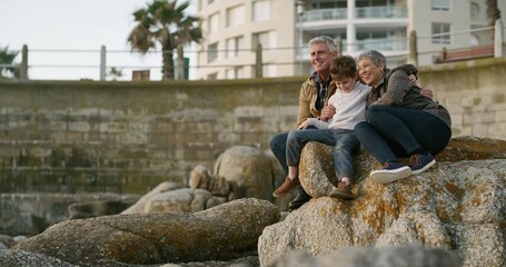 Poster - Family, grandparents and beach while a little boy has fun with his grandmother and grandfather while sitting on rocks and watching the ocean. Elderly couple and grandson enjoying their vacation