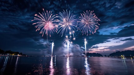 Poster - A beautiful night sky with three fireworks in the air. The fireworks are lit up in red and blue colors. The sky is cloudy and the water is calm