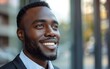 © imagineRbc - A smiling businessman stands outside a contemporary office building, exuding confidence and professionalism against an urban backdrop