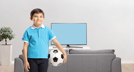 Sticker - Smiling boy holding a football at home in front of tv