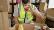 © Krakenimages.com - A young hispanic man with a beard wearing a safety vest holds a heart in a warehouse.
