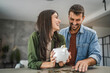 © Miljan Živković - Adult couple save money coins in the piggy bank at home