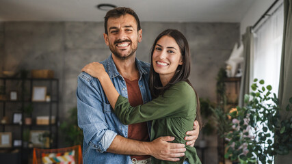 Portrait of beautiful couple stand, smile and hug at home