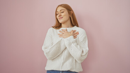 Portrait of a content young caucasian woman in a white sweater over pink background