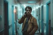 © Mandeep - A young man in a brown jacket, standing in a hallway with a phone to his ear.